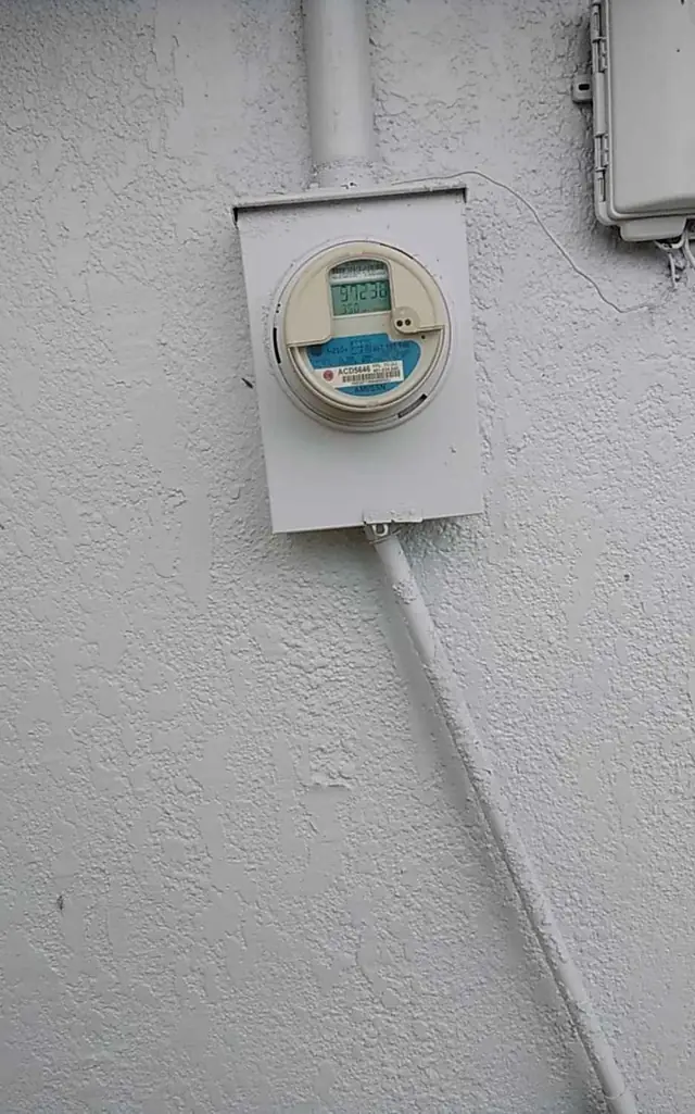 Electric meter and conduit on a painted block wall
