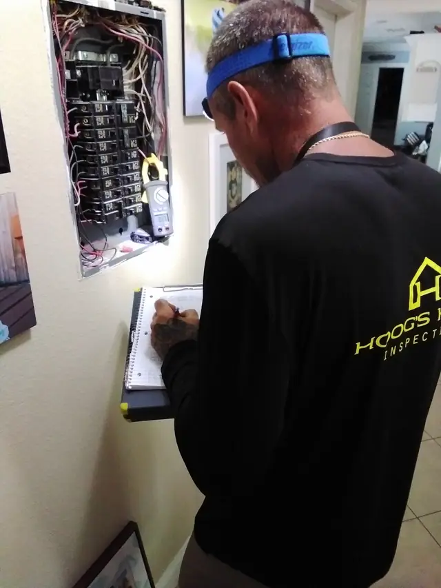 Inspector with a clipboard reading an open interior breaker panel
